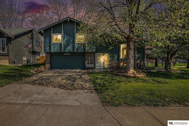 view of front of property featuring a lawn, an attached garage, concrete driveway, and brick siding