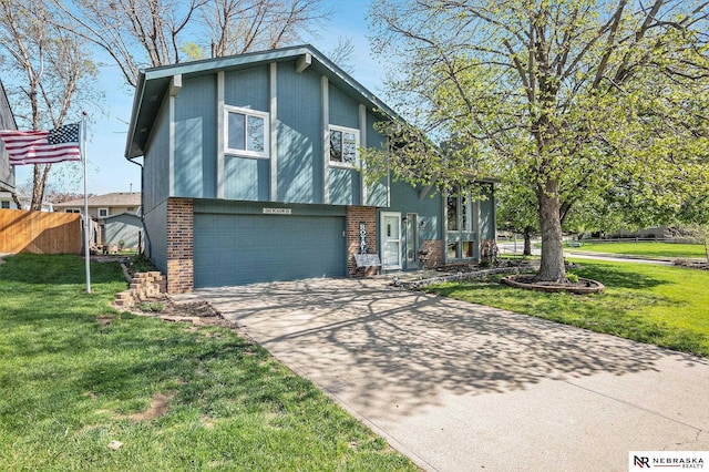 tri-level home with fence, an attached garage, driveway, and a front lawn