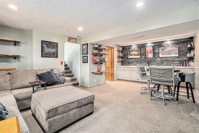 living area featuring a textured ceiling, wet bar, light colored carpet, and recessed lighting