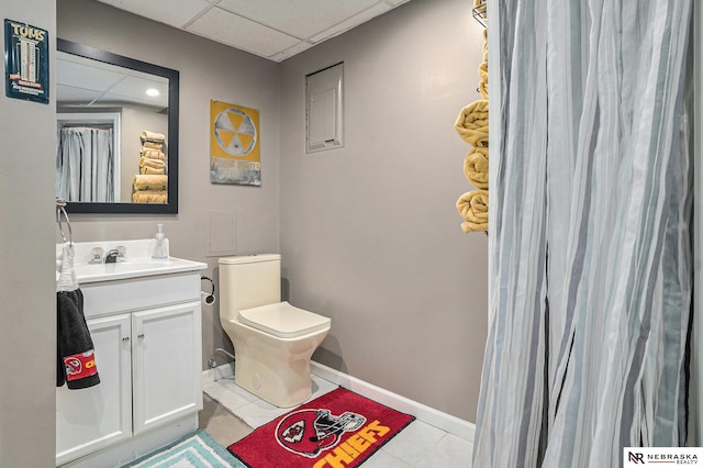 bathroom featuring vanity, a drop ceiling, tile patterned floors, and toilet