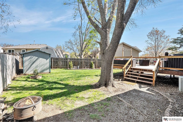 view of yard featuring a fenced backyard, a storage unit, a wooden deck, and an outdoor structure
