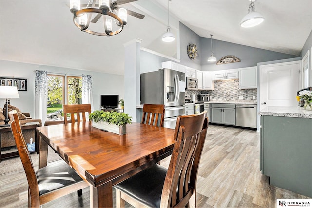 dining area featuring light wood-style floors and high vaulted ceiling