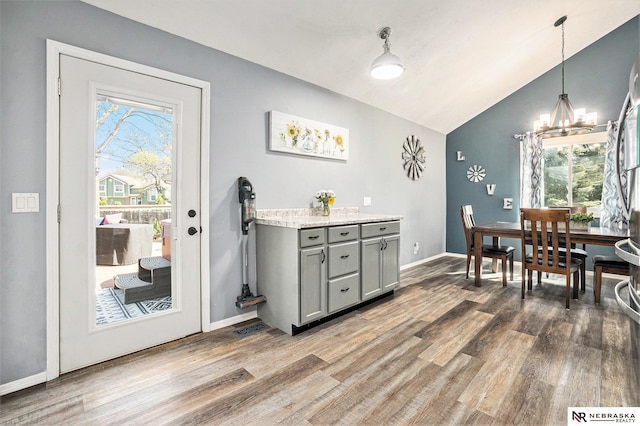 dining space featuring baseboards, an inviting chandelier, wood finished floors, and high vaulted ceiling