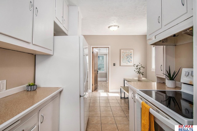 kitchen with light countertops, white cabinetry, light tile patterned flooring, and white appliances