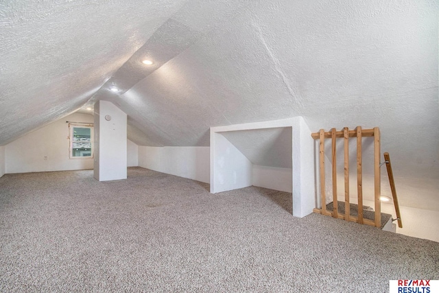additional living space with carpet flooring, a textured ceiling, and lofted ceiling
