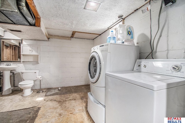 laundry area featuring laundry area, visible vents, washing machine and dryer, concrete block wall, and a sink