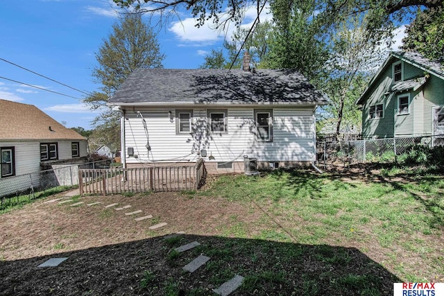 rear view of house featuring a yard, a shingled roof, a chimney, and a fenced backyard