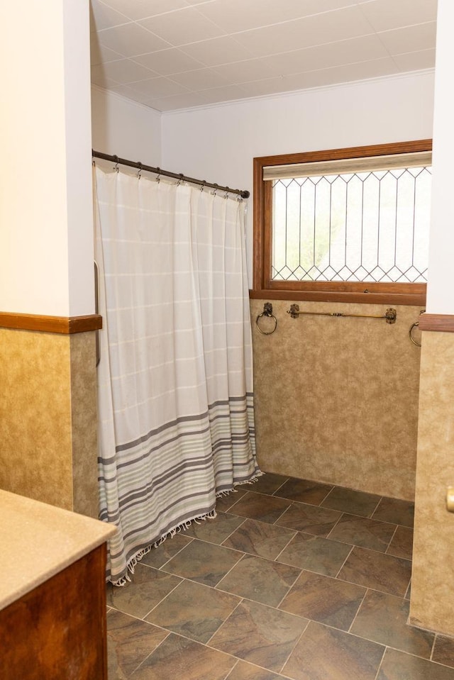 650 E 9th St, York, NE 68467 - bathroom with stone finish flooring, a shower with shower curtain, and wainscoting