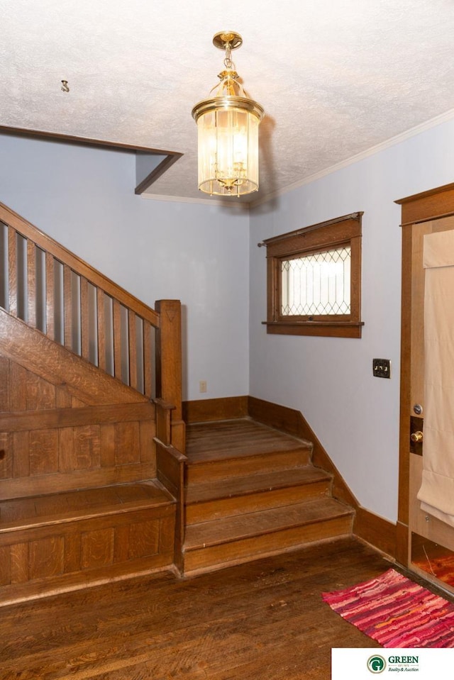 650 E 9th St, York, NE 68467 - staircase featuring baseboards, wood finished floors, an inviting chandelier, and ornamental molding