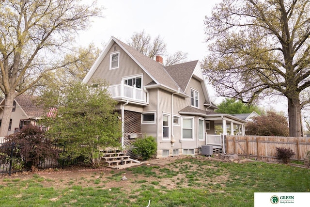 650 E 9th St, York, NE 68467 - back of property with a balcony, a chimney, roof with shingles, central air condition unit, and fence