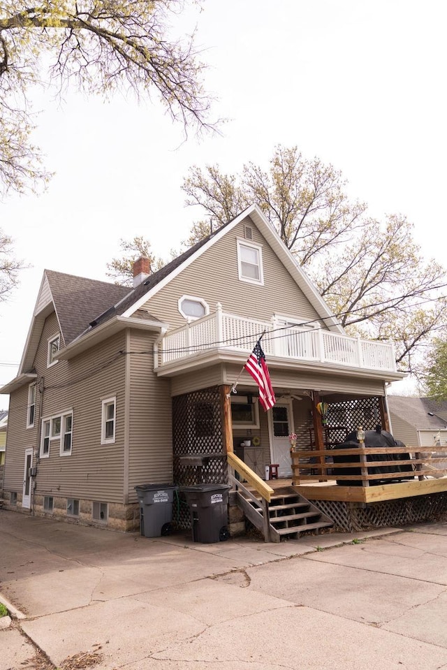 650 E 9th St, York, NE 68467 - view of front facade featuring a chimney, a shingled roof, a deck, and a balcony