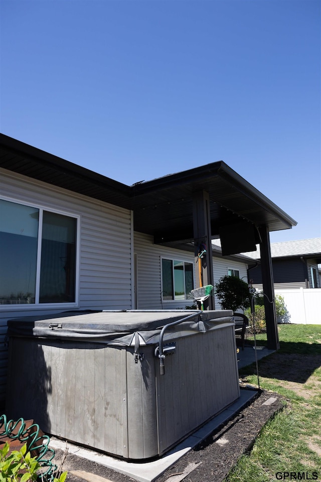 view of patio with a hot tub and fence