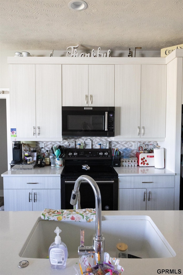 kitchen featuring a textured ceiling, black range with electric cooktop, and light countertops