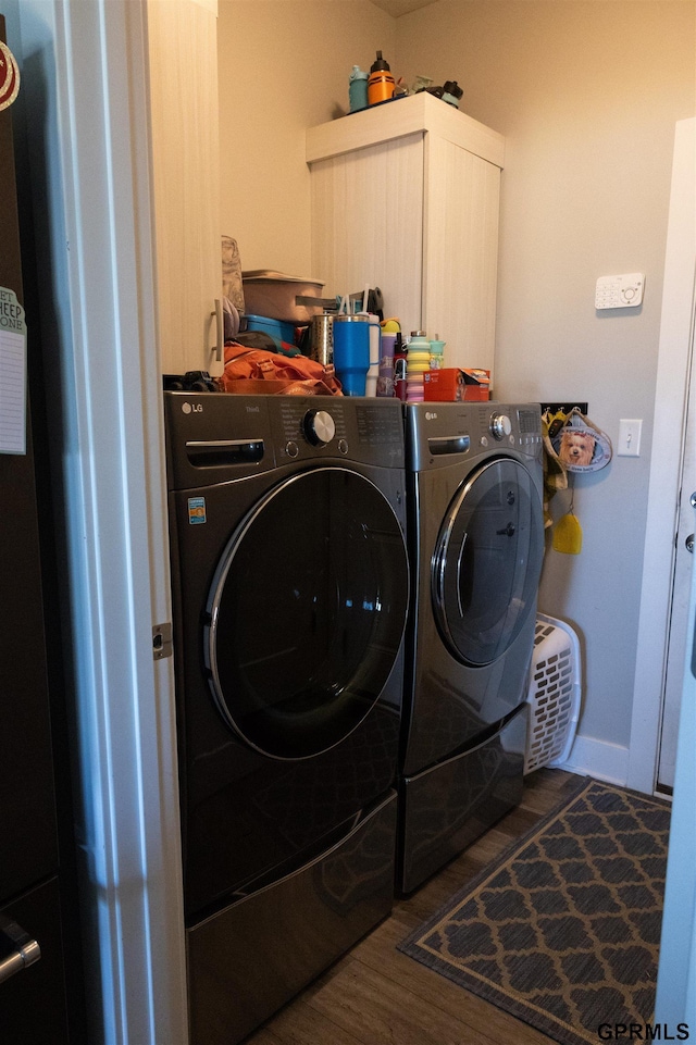 laundry area with washer and clothes dryer, cabinet space, baseboards, and wood finished floors