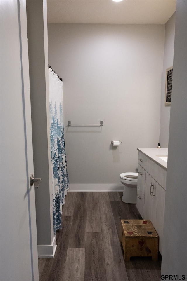 bathroom featuring vanity, toilet, baseboards, and wood finished floors