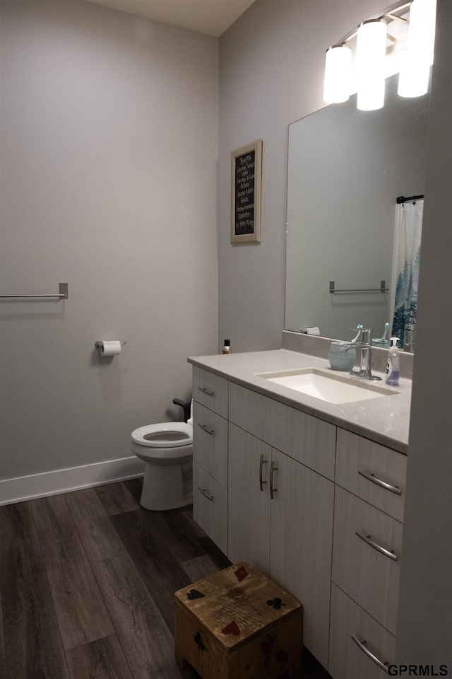 bathroom with vanity, toilet, baseboards, and wood finished floors
