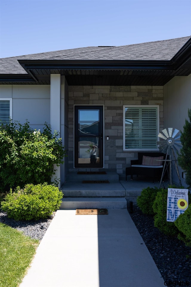 doorway to property featuring a porch and roof with shingles