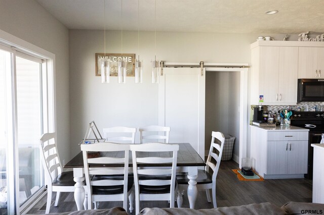 dining room featuring a barn door, dark wood-style floors, a healthy amount of sunlight, and recessed lighting
