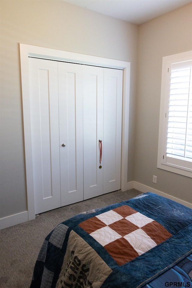 carpeted bedroom featuring baseboards and a closet