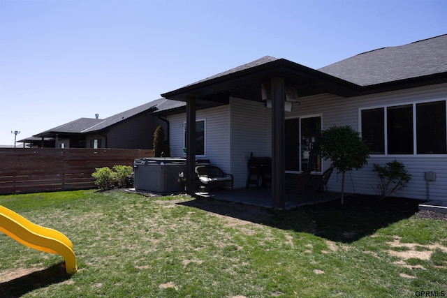 rear view of house featuring a patio area, fence, a shingled roof, a lawn, and a playground