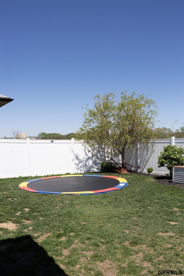 view of yard with a trampoline and a fenced backyard