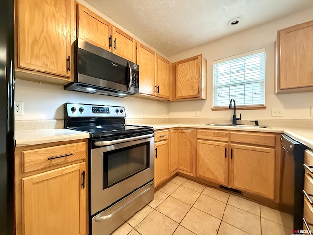 kitchen featuring black appliances, light tile patterned flooring, light countertops, and a sink