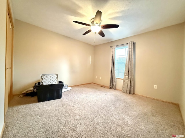 carpeted spare room with baseboards and ceiling fan