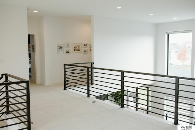 hallway featuring carpet floors, recessed lighting, and an upstairs landing