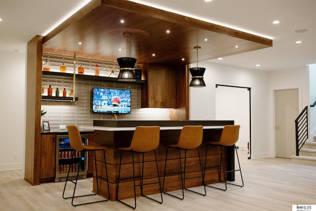 bar with wine cooler, bar area, light wood-style flooring, and tasteful backsplash