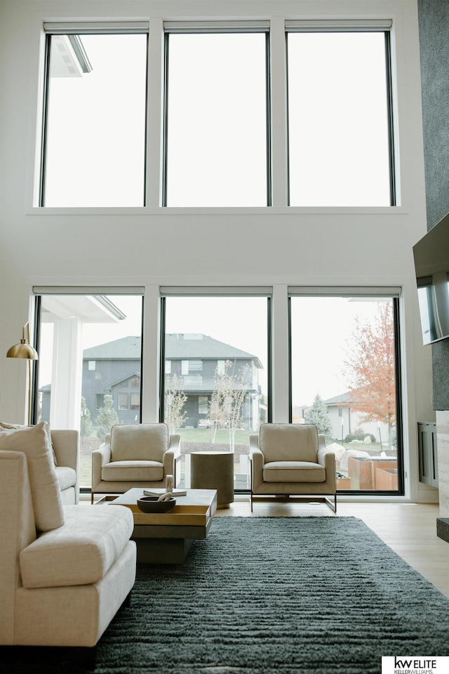 living room with plenty of natural light, wood finished floors, and a towering ceiling