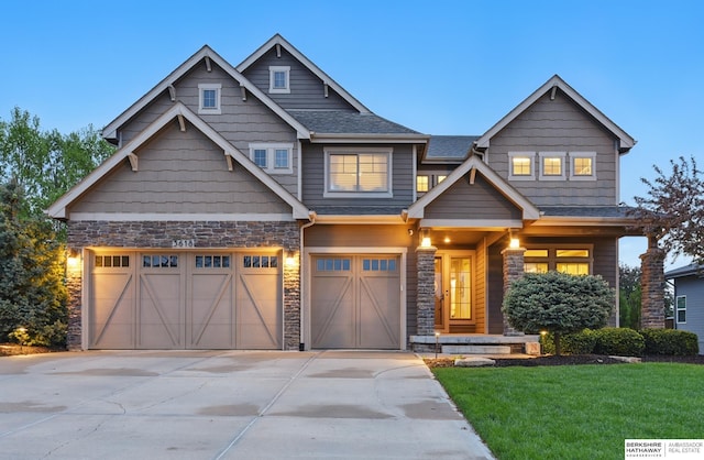 craftsman inspired home featuring a garage, a front yard, stone siding, a shingled roof, and concrete driveway