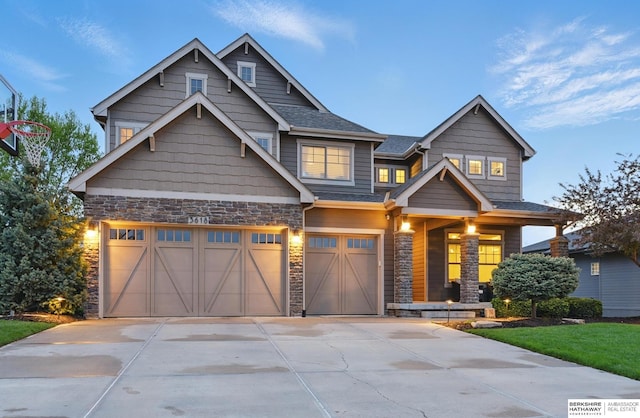 craftsman house with concrete driveway, an attached garage, covered porch, and stone siding