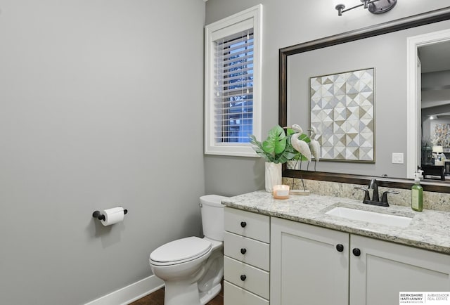 bathroom featuring toilet, baseboards, a healthy amount of sunlight, and vanity