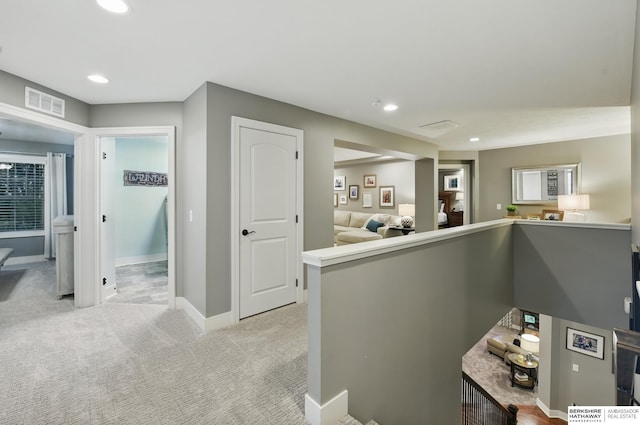 corridor featuring light colored carpet, baseboards, visible vents, and recessed lighting