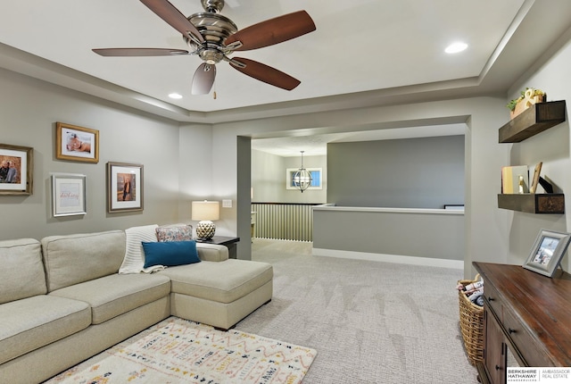 living room featuring light colored carpet, recessed lighting, baseboards, and ceiling fan with notable chandelier