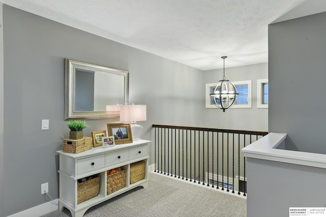 hallway featuring an inviting chandelier, baseboards, and carpet flooring