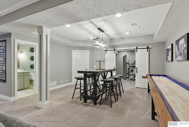 dining area featuring light colored carpet, a barn door, baseboards, and visible vents