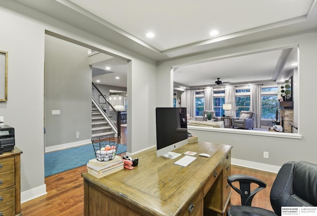 home office featuring baseboards, ceiling fan, a tray ceiling, and wood finished floors