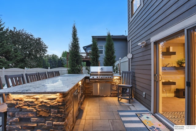 view of patio featuring a fenced backyard, outdoor wet bar, exterior kitchen, and area for grilling