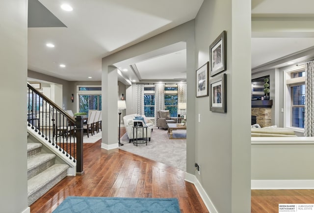 entrance foyer featuring a stone fireplace, wood finished floors, stairway, baseboards, and recessed lighting