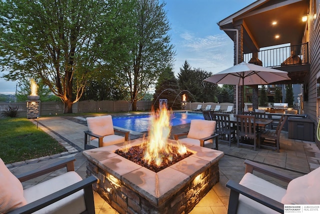 view of patio featuring outdoor dining area, a fenced in pool, a balcony, a fenced backyard, and an outdoor fire pit