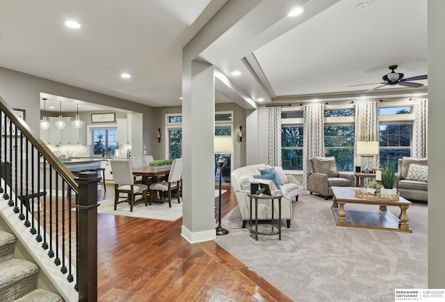 living area with recessed lighting, ceiling fan, wood finished floors, and stairway