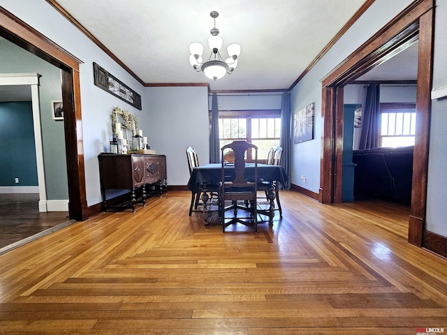 dining space with an inviting chandelier, crown molding, and baseboards