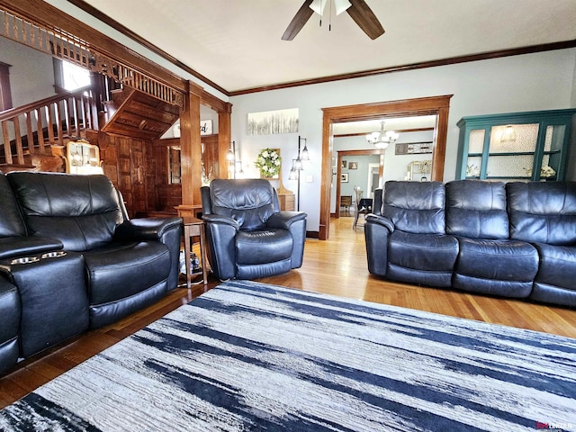 living area featuring crown molding, stairway, baseboards, wood finished floors, and ceiling fan with notable chandelier