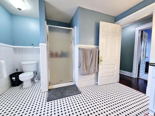 full bathroom featuring toilet, a stall shower, and wainscoting