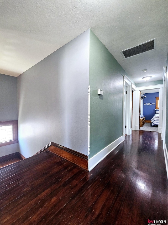 corridor with visible vents, baseboards, and wood-type flooring