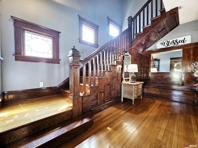 stairway with a towering ceiling and hardwood / wood-style floors