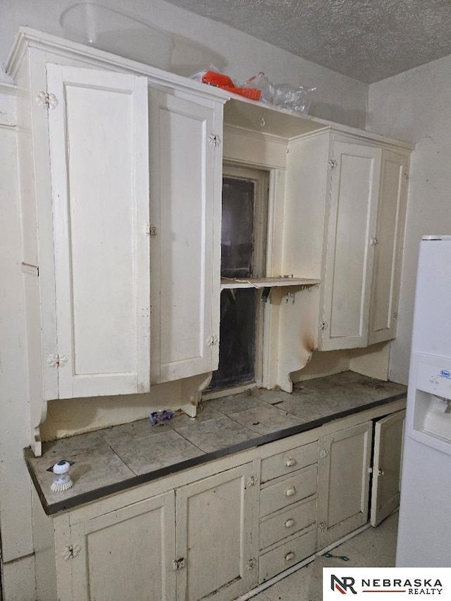 kitchen with white fridge with ice dispenser and white cabinets