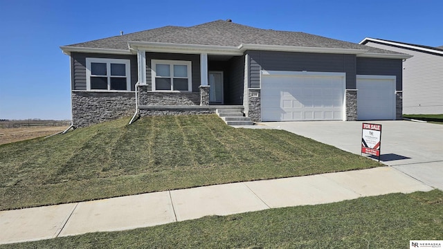 view of front of property featuring driveway, stone siding, an attached garage, a porch, and a front lawn