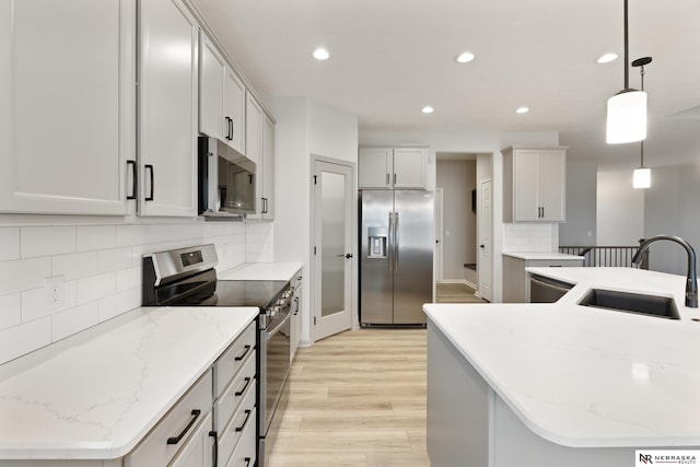 kitchen with recessed lighting, light wood-style flooring, appliances with stainless steel finishes, backsplash, and a sink